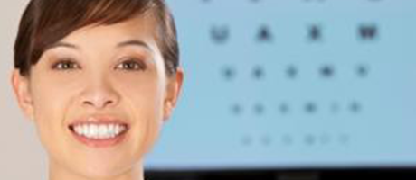 woman smiling in front of eye exam chart